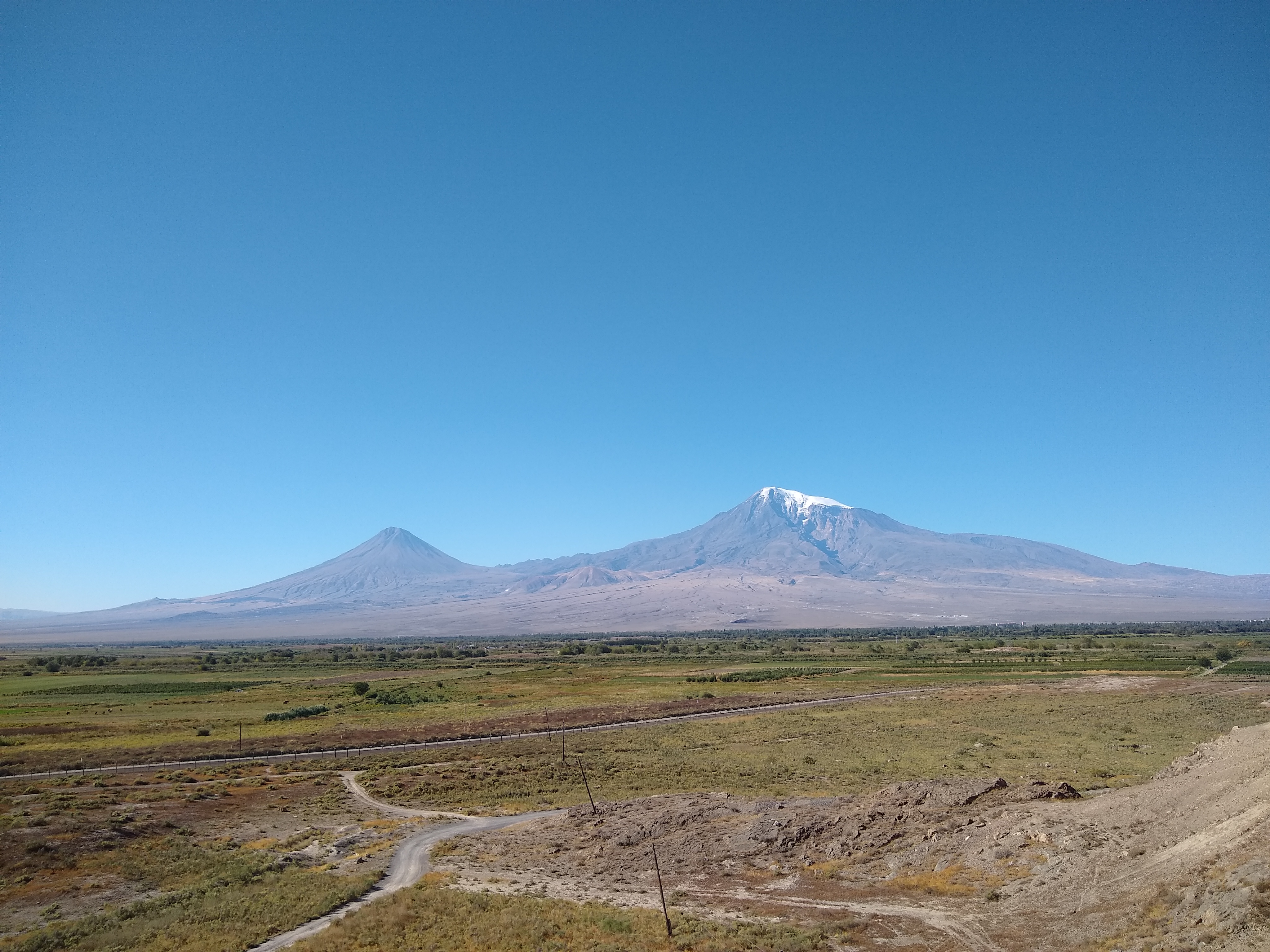 Photo of a mountain in the distance with a green plain in front of it