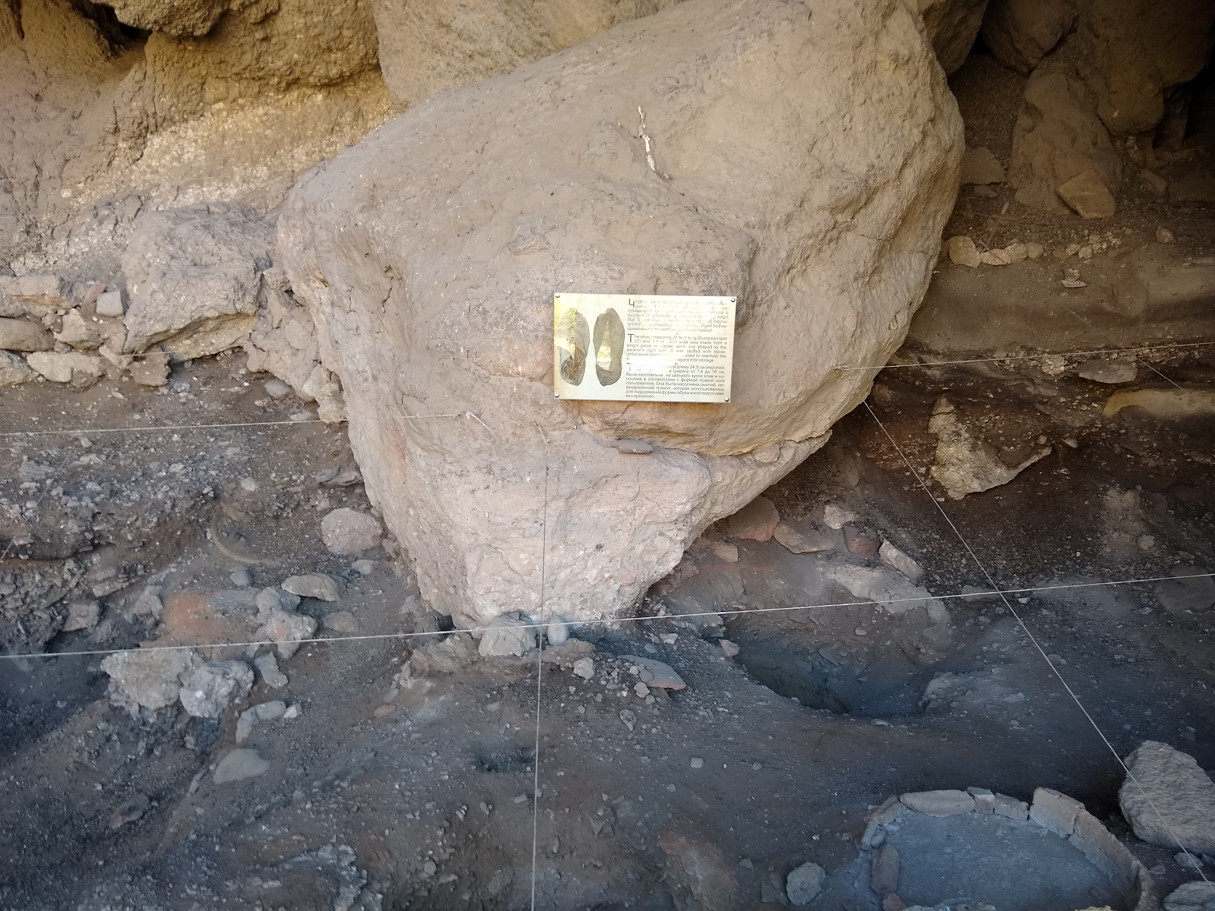 A photo a rock in a cave, with a sign describing a shoe