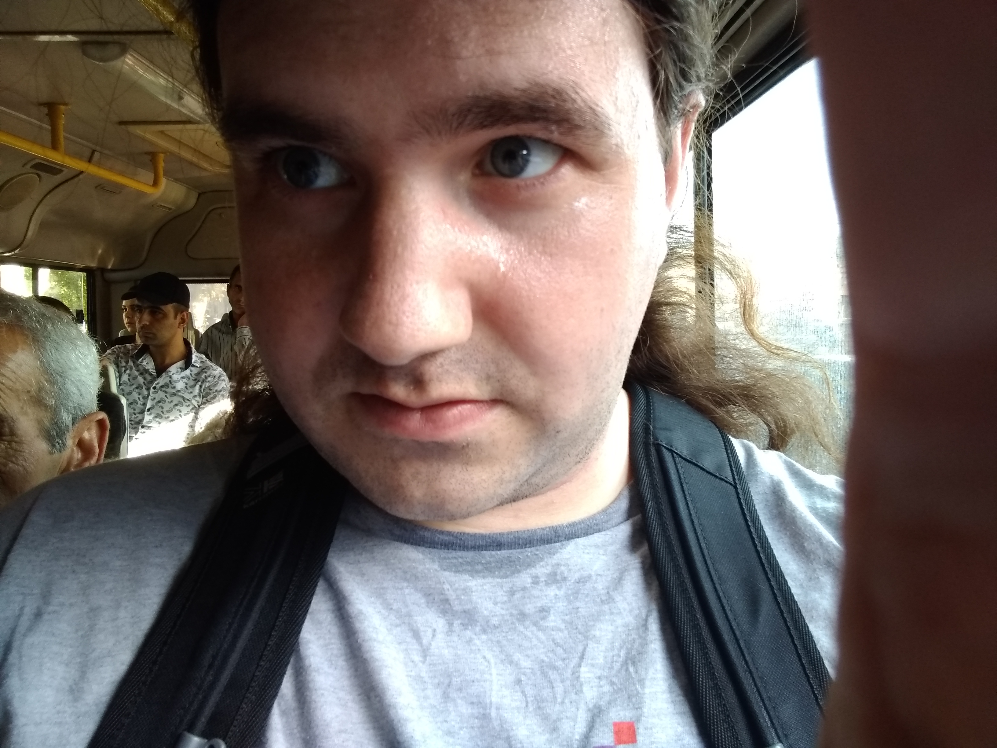 Photo of a man wearing a back pack on a crowded bus