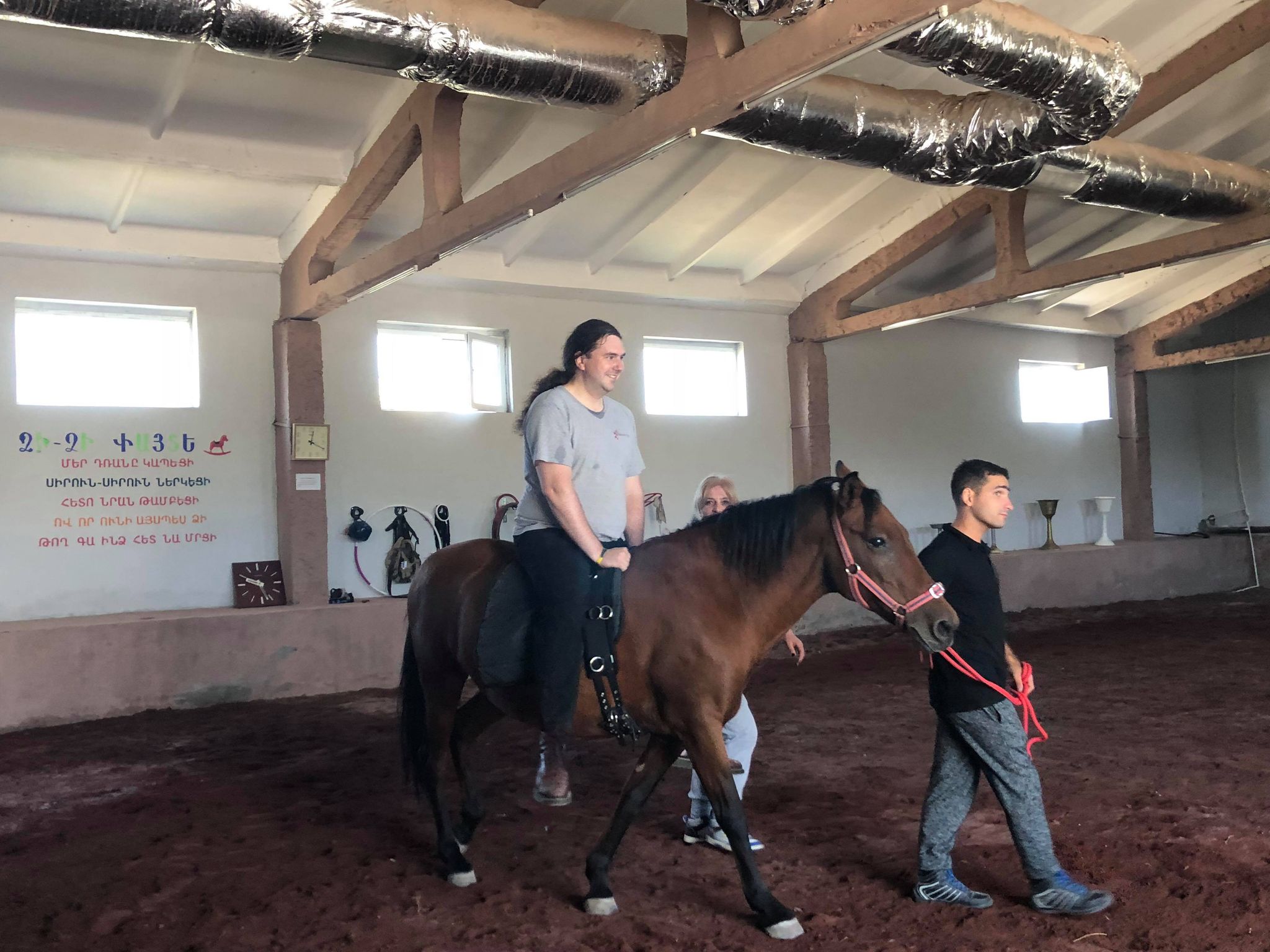 Photo of a man riding a horse, with people helping guide the horse