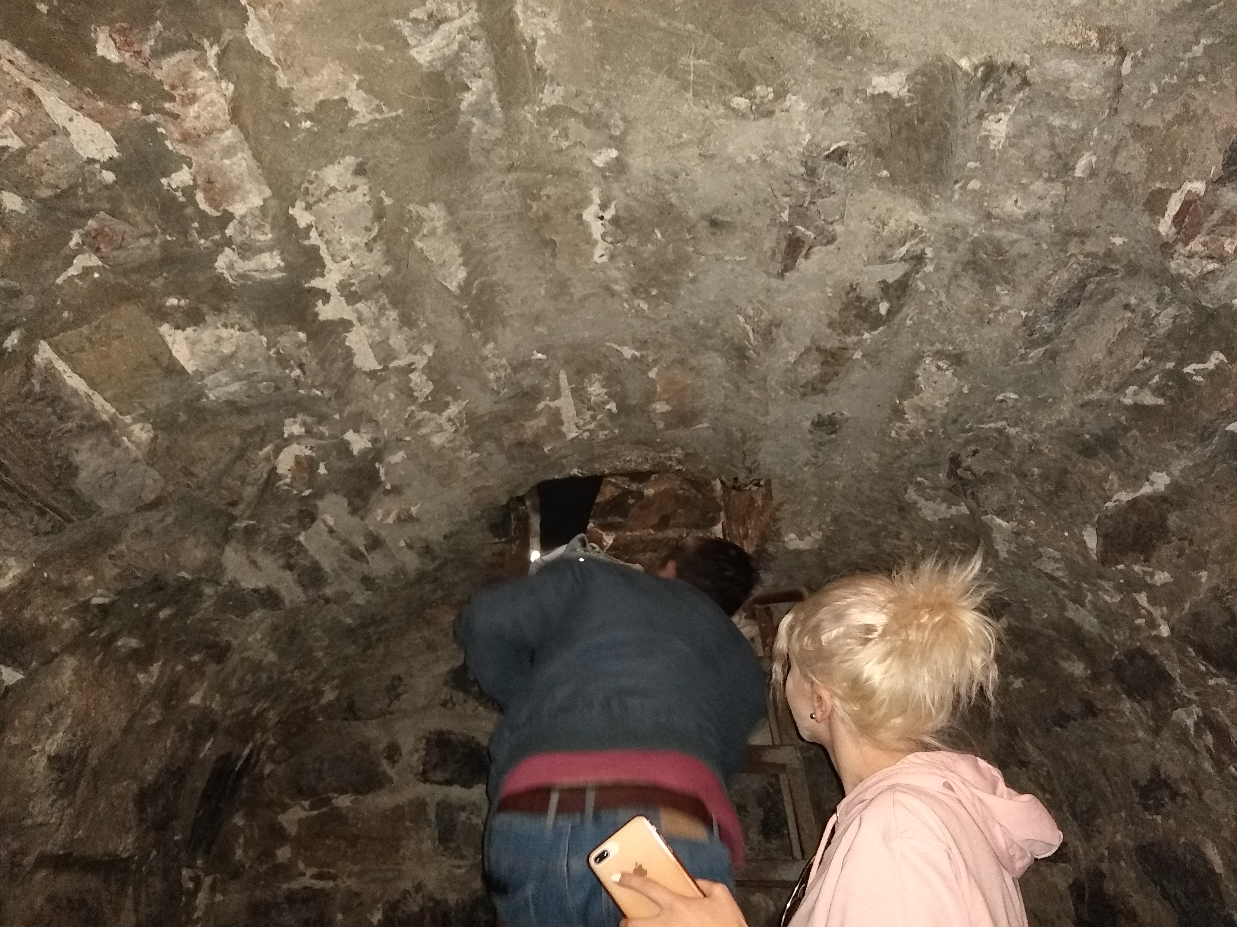 Photo of people climbing a ladder into a small hole in the ceiling