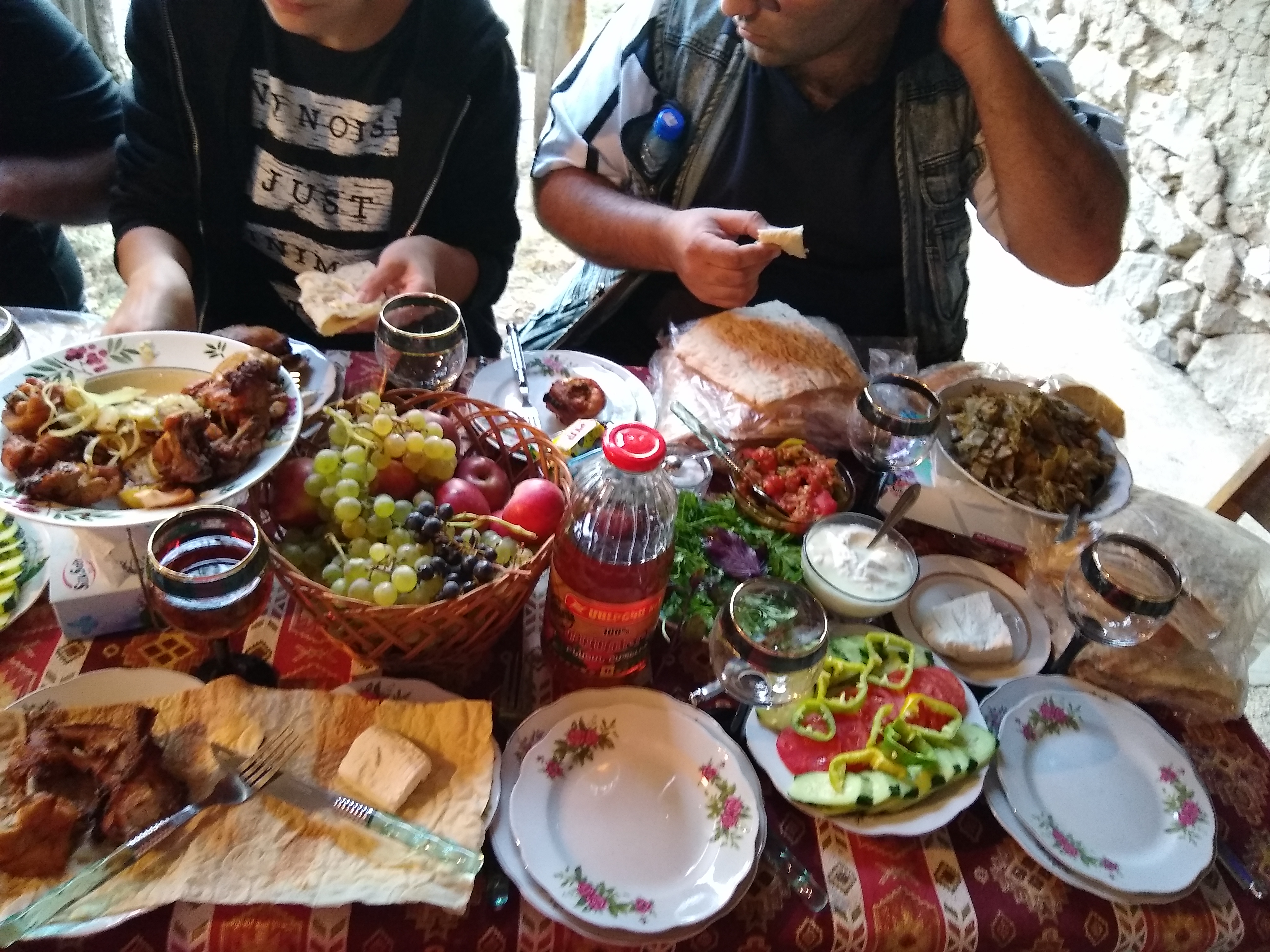 Photo of numerous foods on a table, with people eating